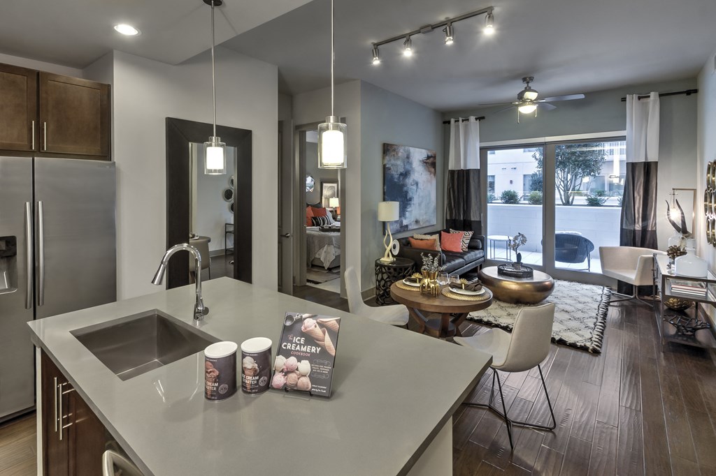 a kitchen with a large center island next to a living room with a couch and a table