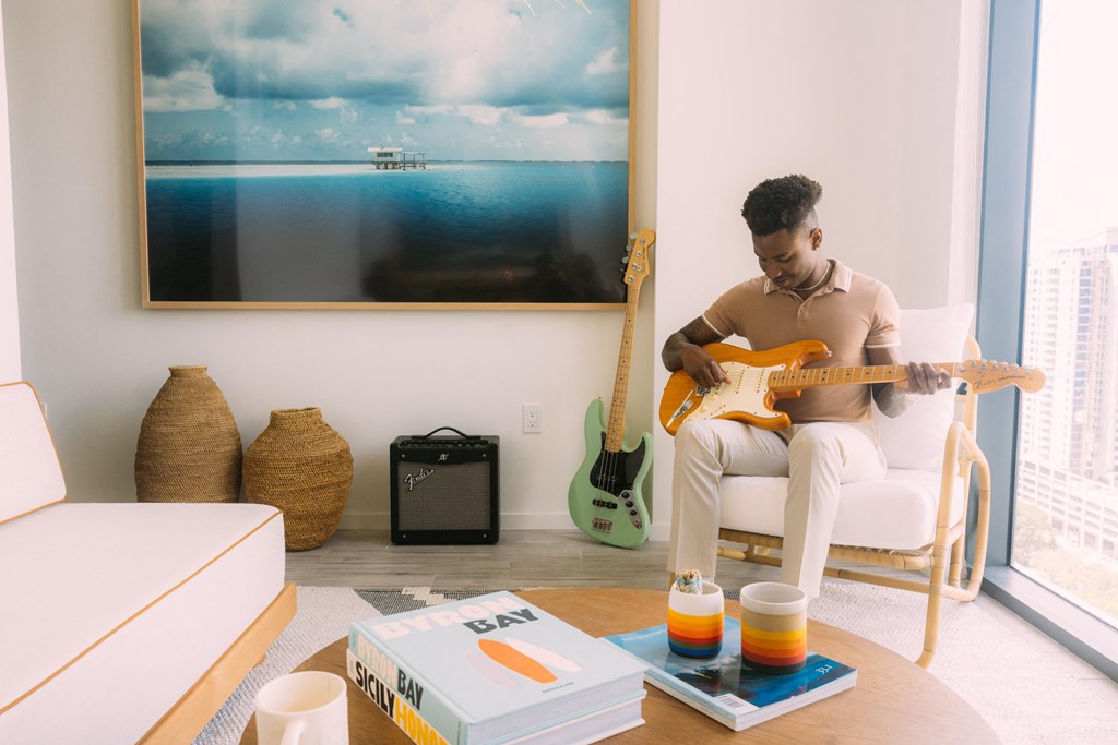 a man sitting in a chair playing a guitar in a living room