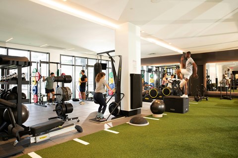 A gym with people working out and various equipment.