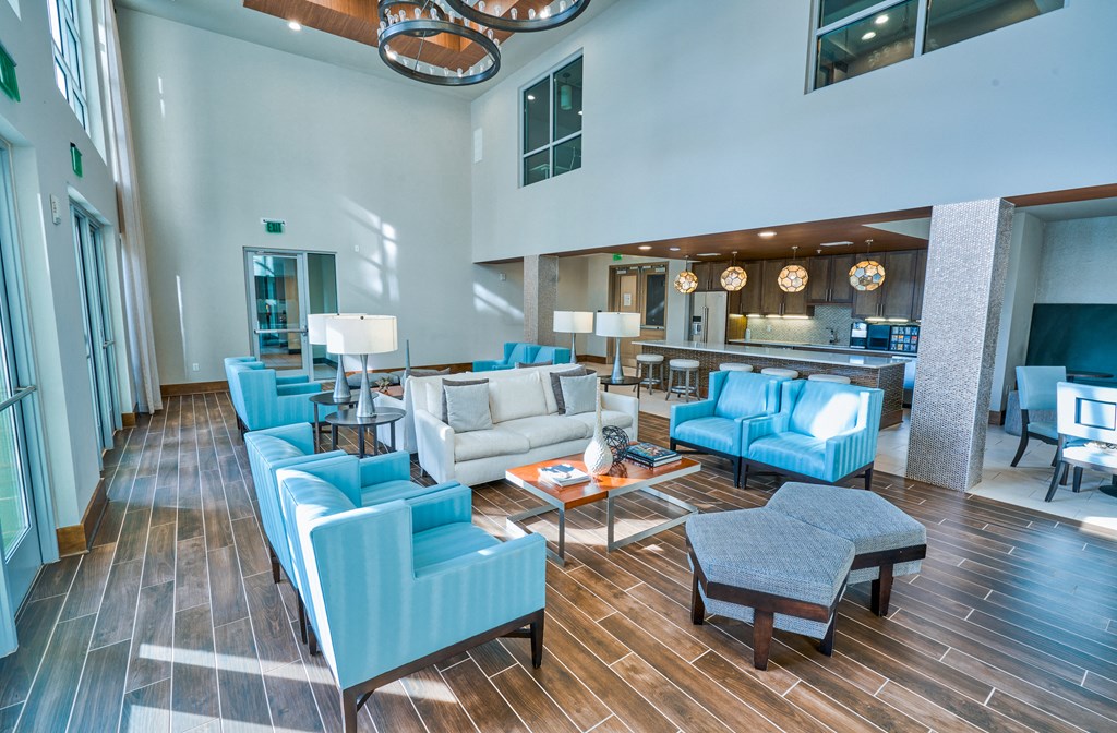 a living room with blue chairs and couches and a kitchen