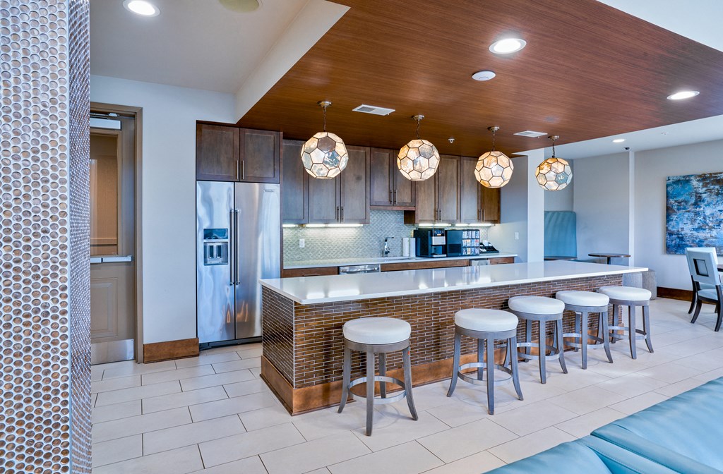 a kitchen with a bar and stools and a refrigerator