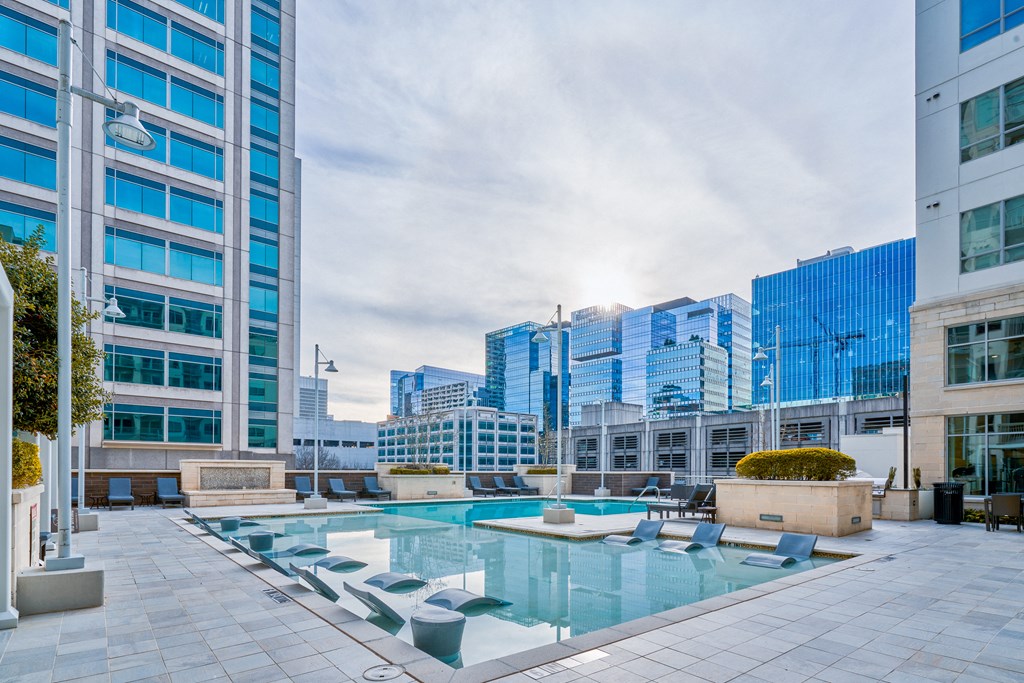 a large pool with lounge chairs in front of tall buildings