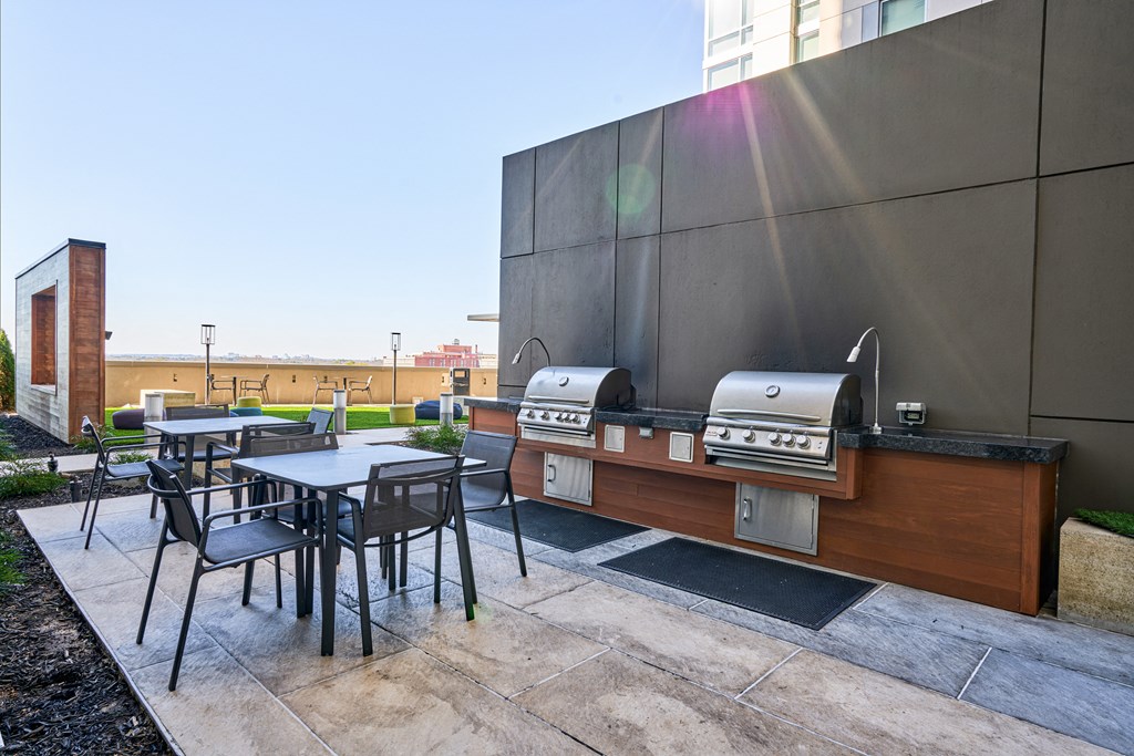 a patio with tables and barbecue grills on the side of a building