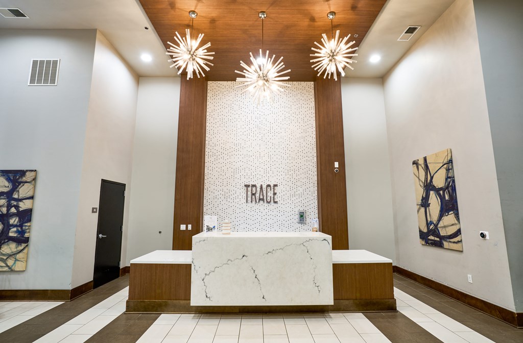 a large lobby with a marble reception desk and two light fixtures