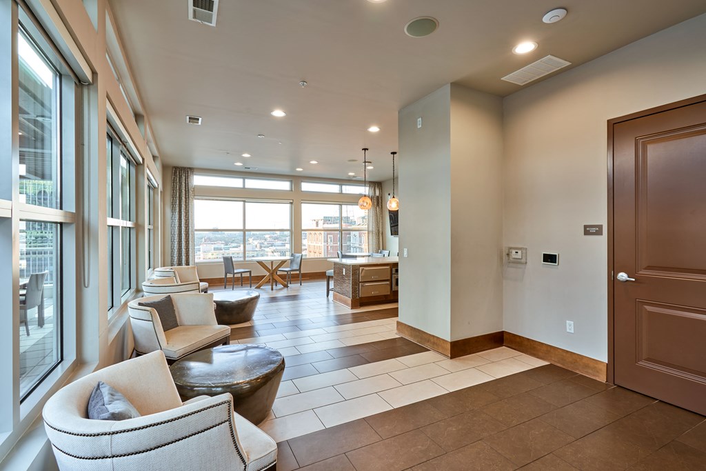 a living room with couches and chairs and a kitchen with windows