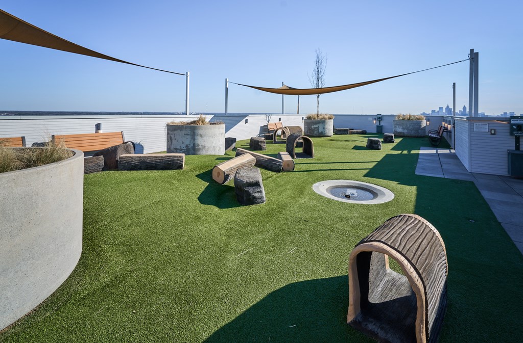 a roof top turf area with chairs and a fire pit