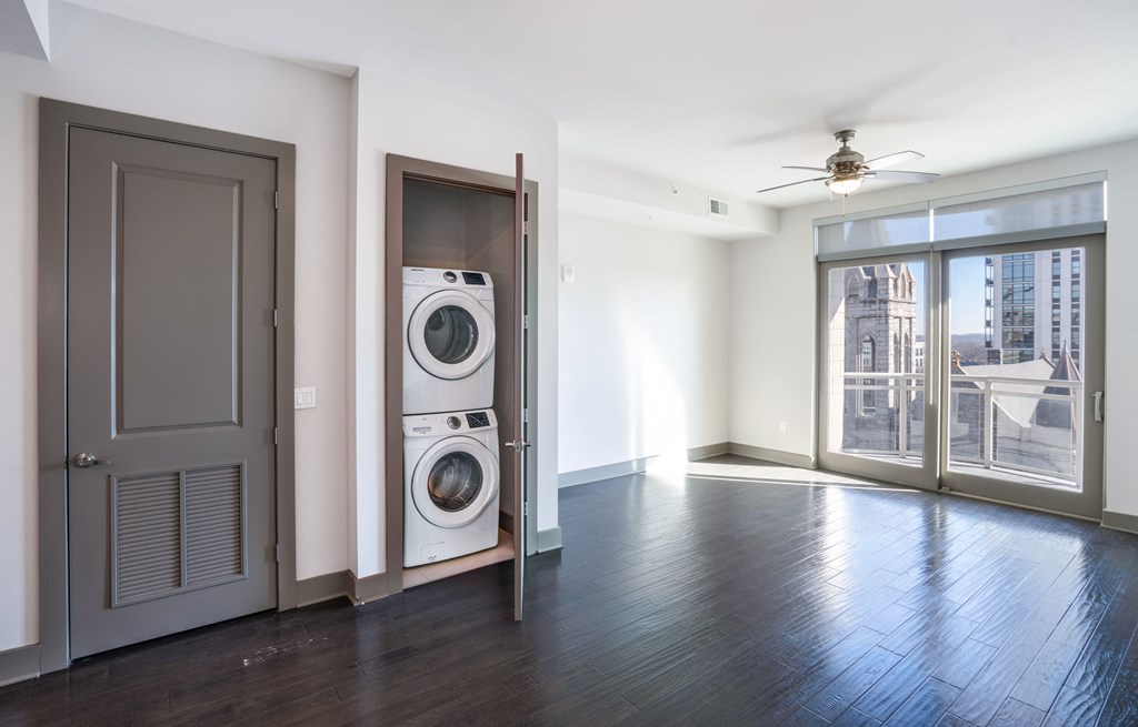 an empty living room with a washer and dryer in it and a window