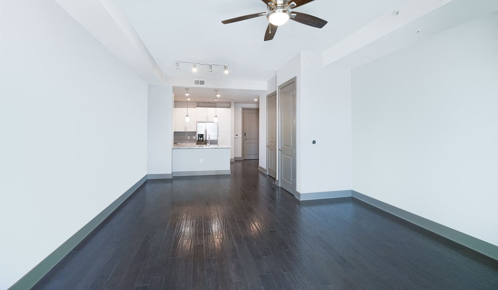 a living room with white walls and a ceiling fan