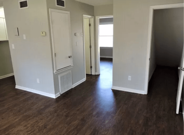 an empty living room with wood flooring and white walls