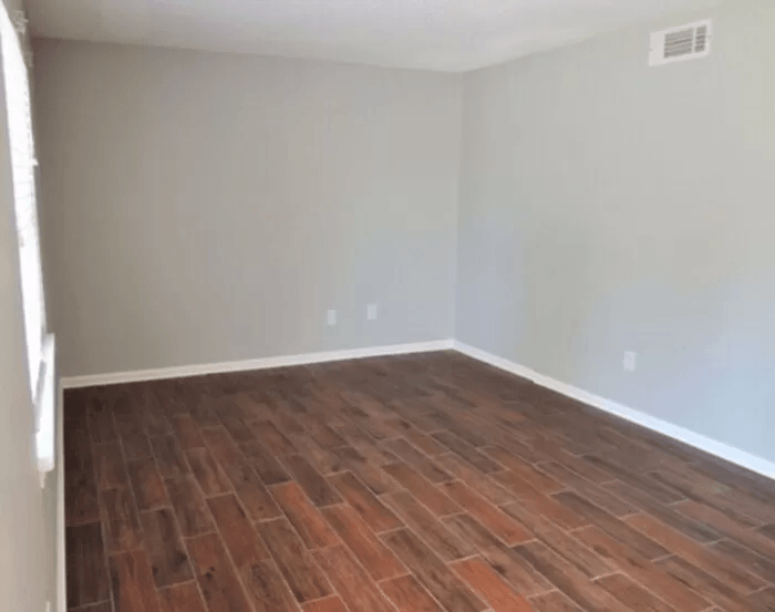 an empty room with wood flooring and white walls