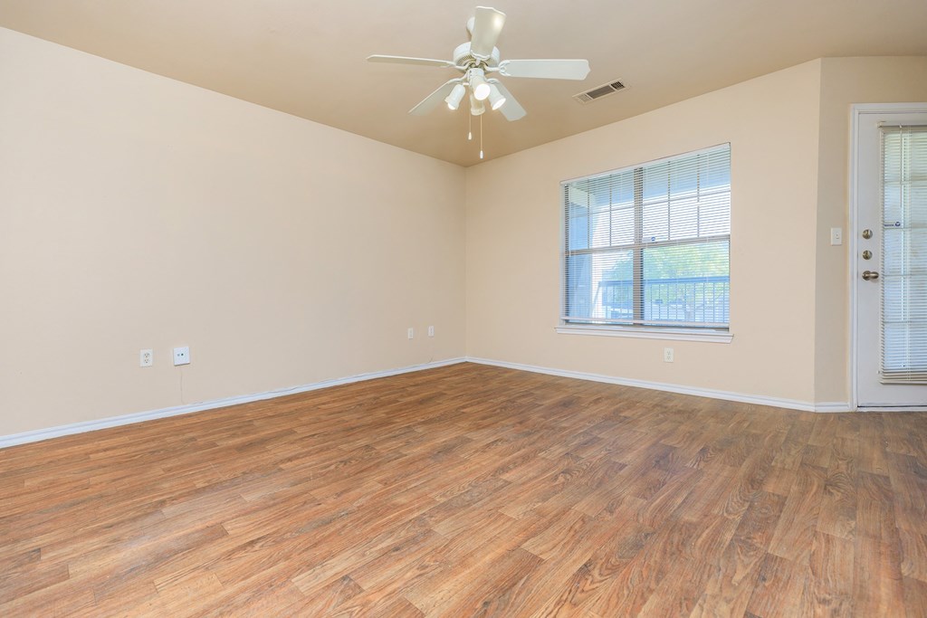an empty living room with wood flooring and a ceiling fan