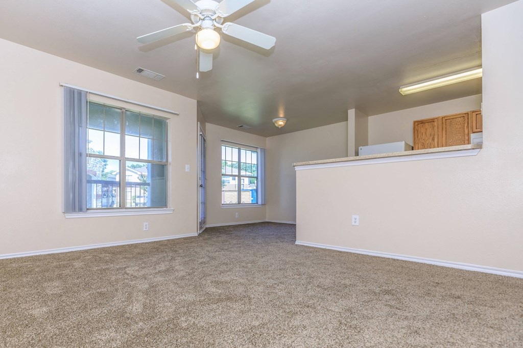 an empty living room with a ceiling fan and a window