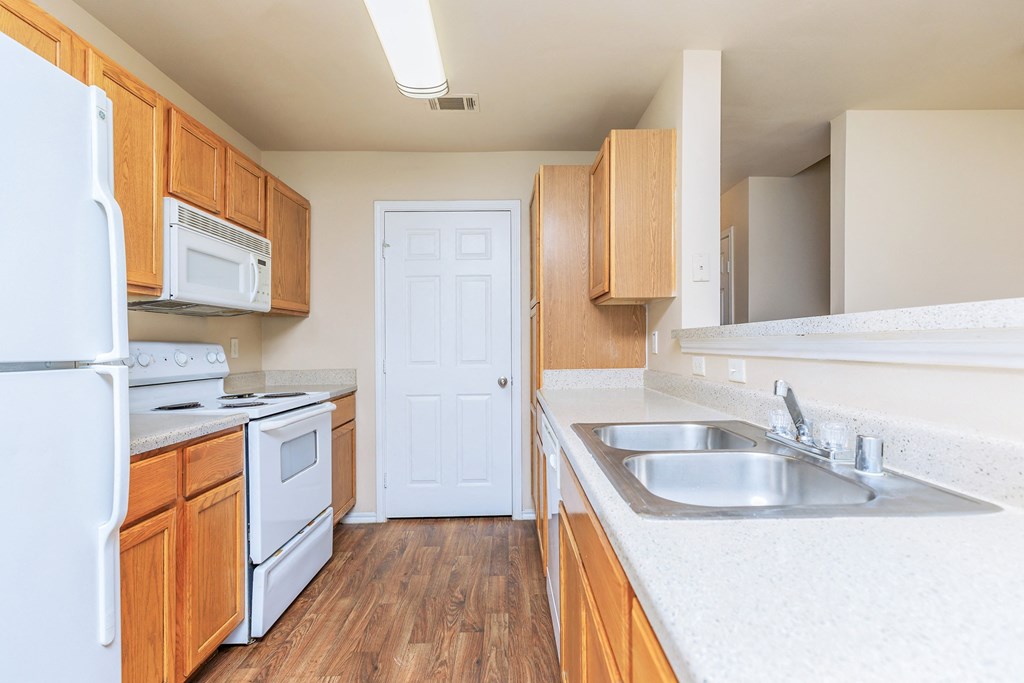 an empty kitchen with white appliances and wooden cabinets