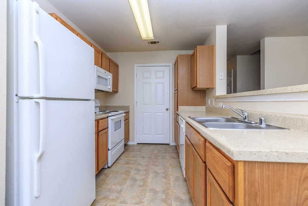 an empty kitchen with a white refrigerator and a sink