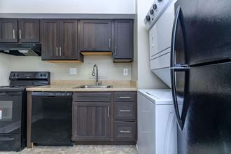 a kitchen with black cabinets and white appliances at Parkland Village, Forestville Maryland