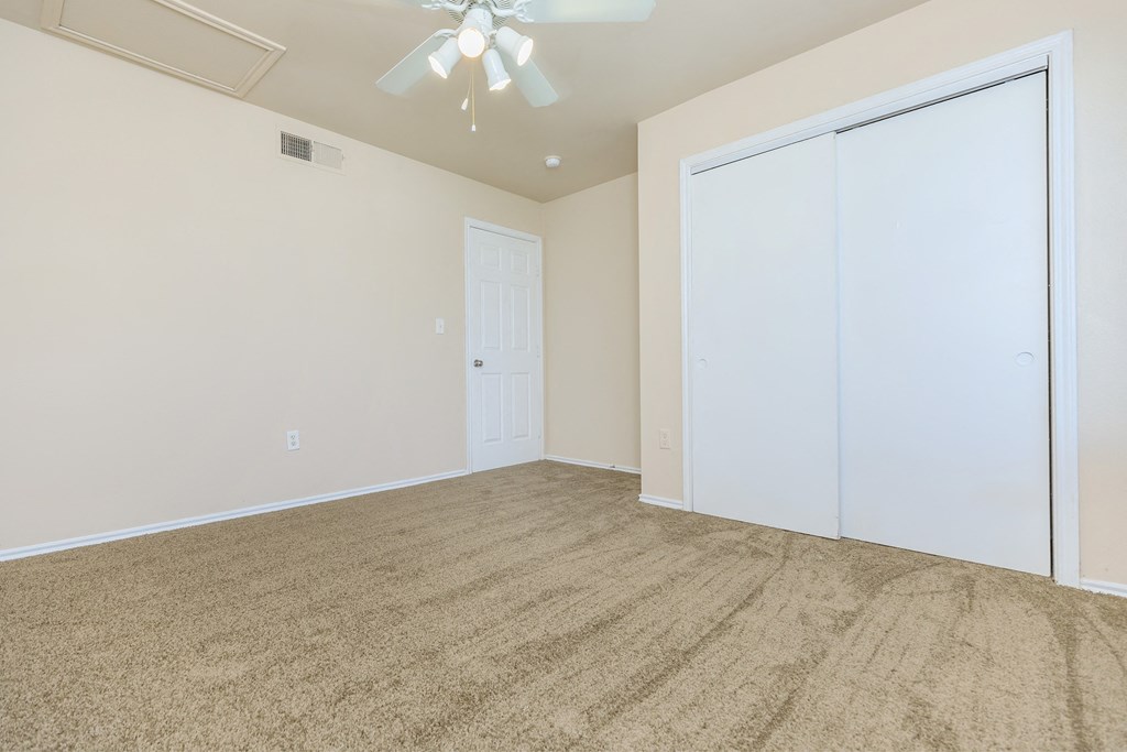 an empty living room with carpet and a ceiling fan