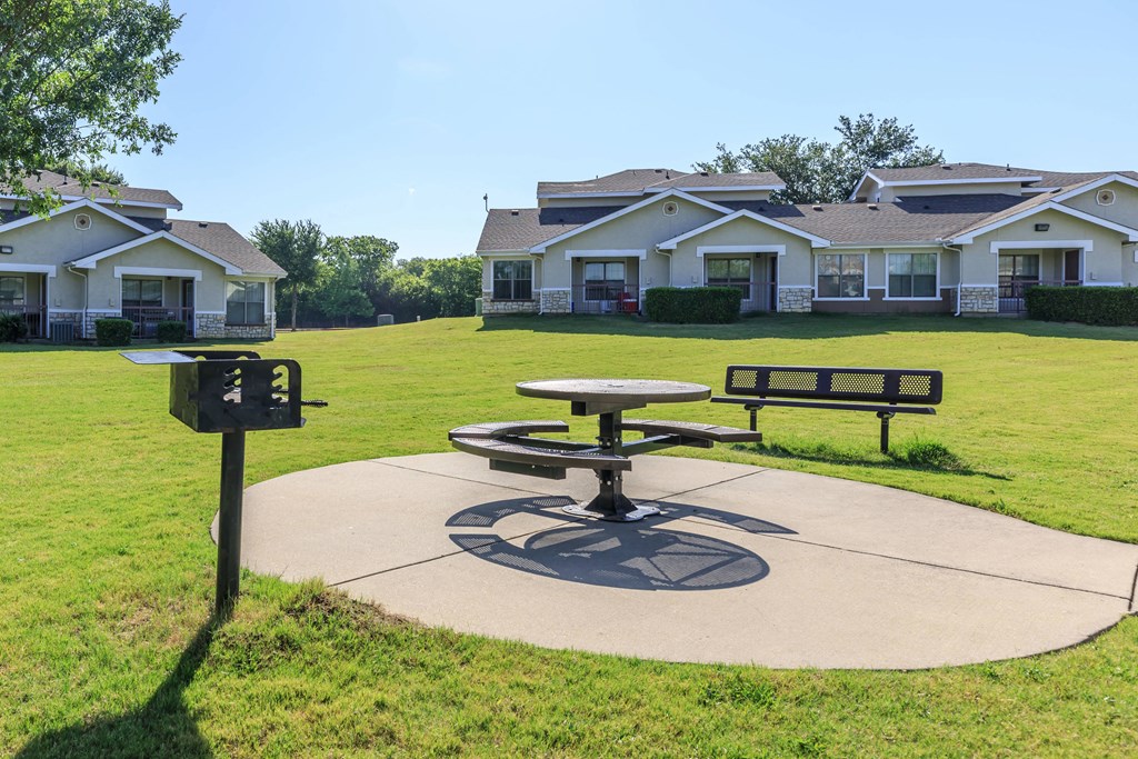 a picnic table in a park with houses in the background