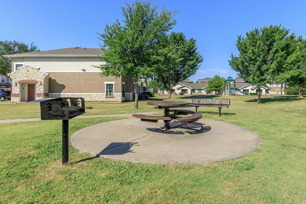 a park with a picnic table and benches in front of a building