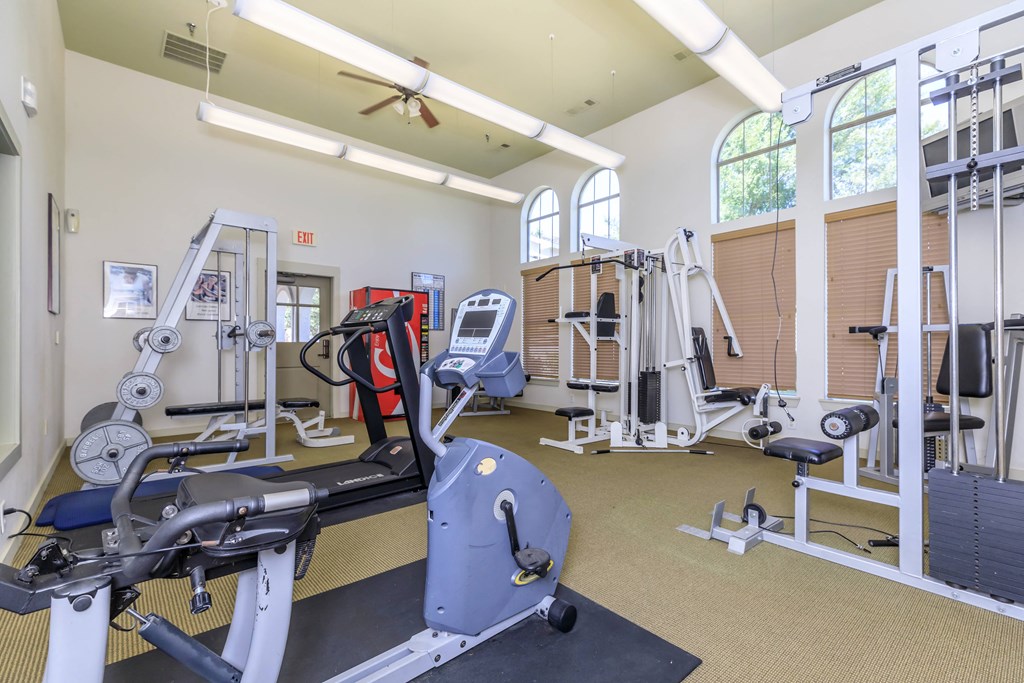 a gym with cardio equipment and weights in a building with windows