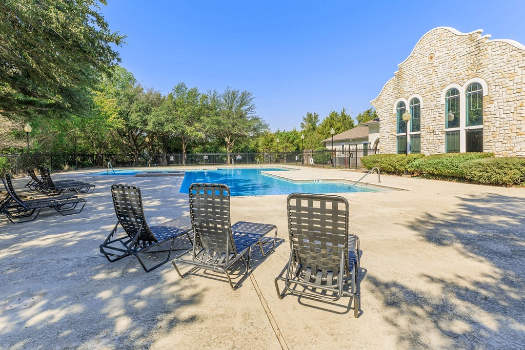 a pool with four rocking chairs next to a swimming pool