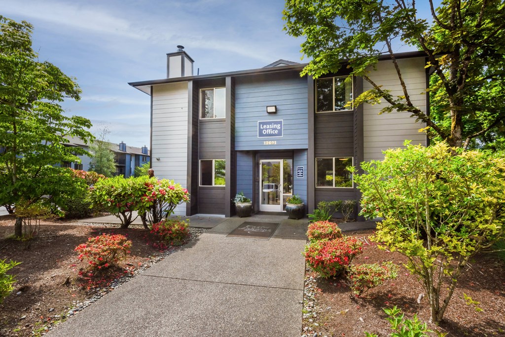 the front of a grey building with a walkway and plants at Eagles Landing Apartments, Everett, 98204