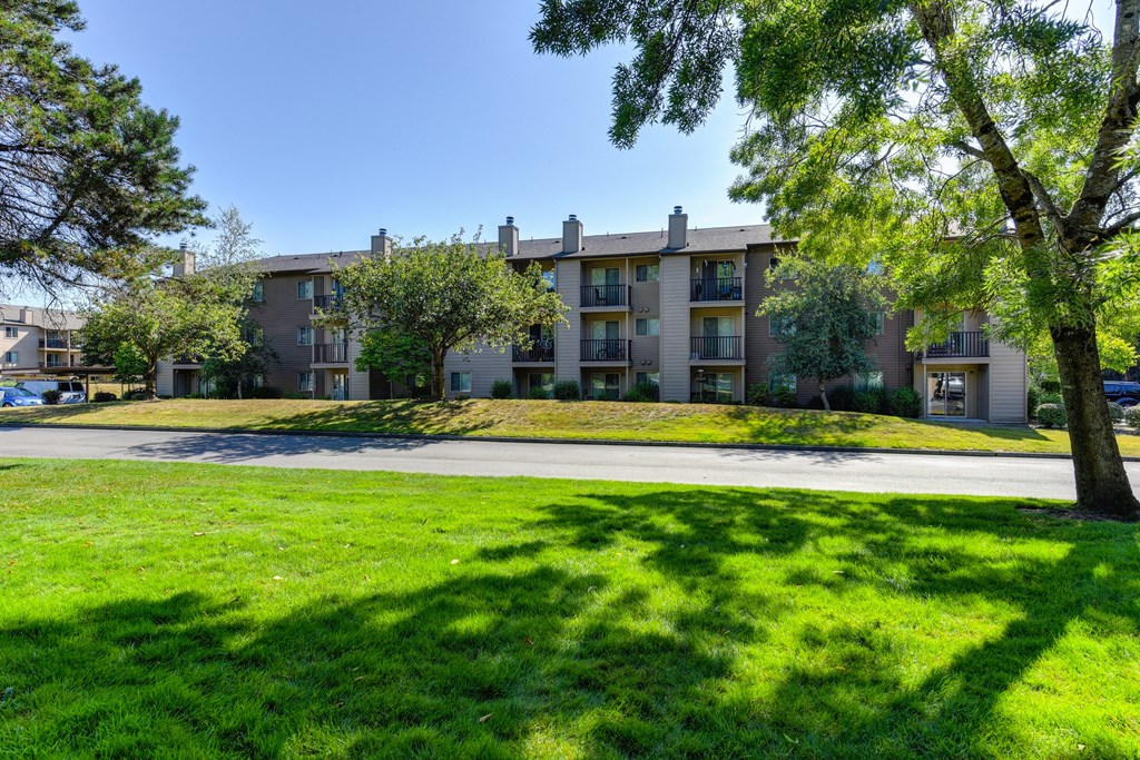 an apartment building with green grass and trees in front of it