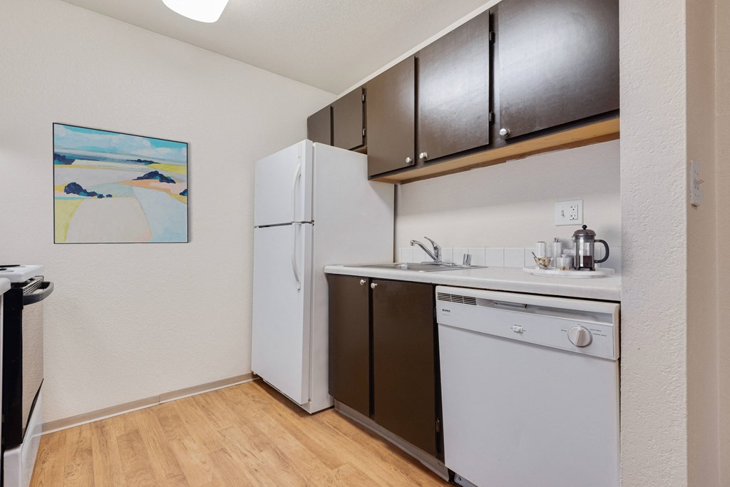 a small kitchen with a white dishwasher and a refrigerator at Eagles Landing Apartments, Everett  