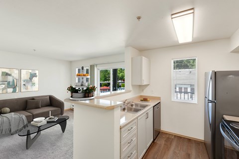 a living room with a couch and a kitchen with a sink at Sage Apartments, Everett, Washington