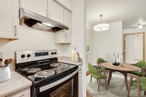 a kitchen with a stove and a dining room with a table and chairs at Sage Apartments, Washington, 98204