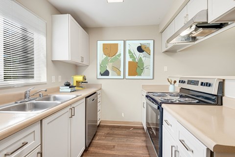 a modern kitchen with white cabinets and stainless steel appliances at Sage Apartments, Washington