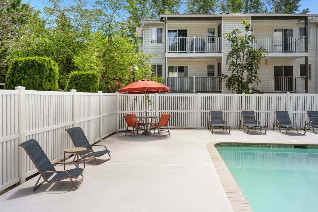 our apartments have a pool and a patio with chairs and an umbrella