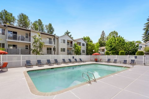 our apartments have a resort style pool with chairs at Sage Apartments, Everett