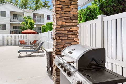 a barbecue grill on a patio with chairs and a fence at Sage Apartments, Everett, 98204