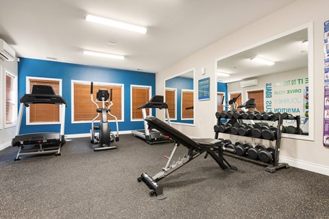 a gym with weights and exercise equipment in a room with blue walls at Sage Apartments, Everett, Washington