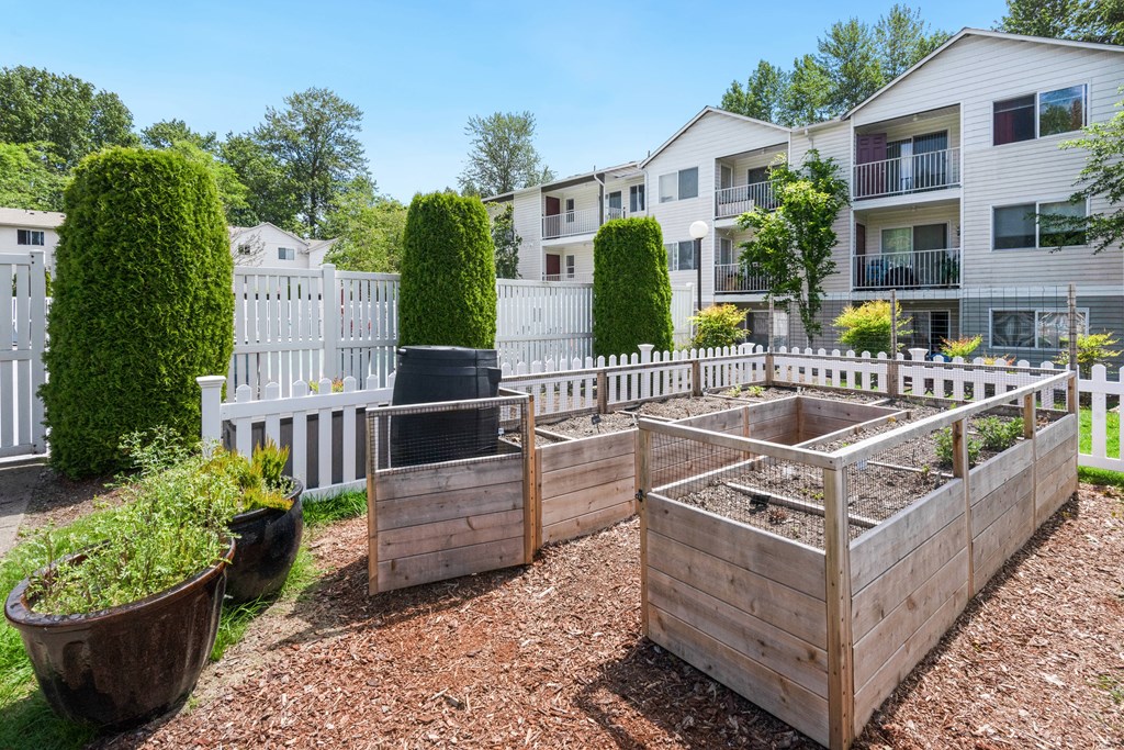 a community garden with raised beds and a white fence