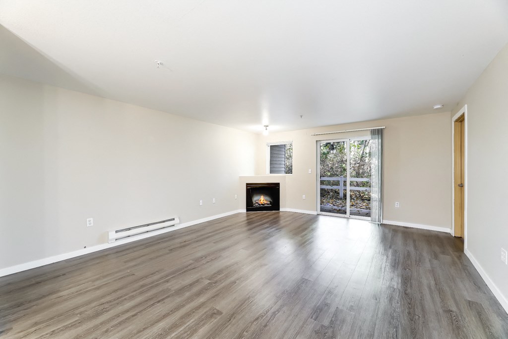 an empty living room with a fireplace and wooden floors