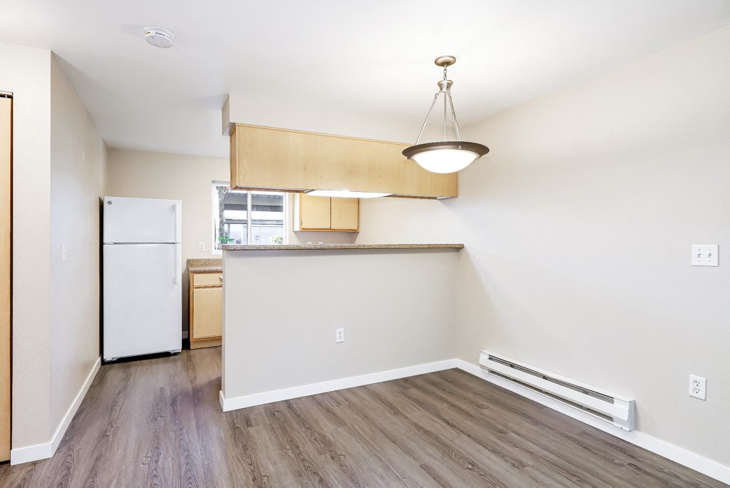 an empty apartment with a kitchen and a refrigerator