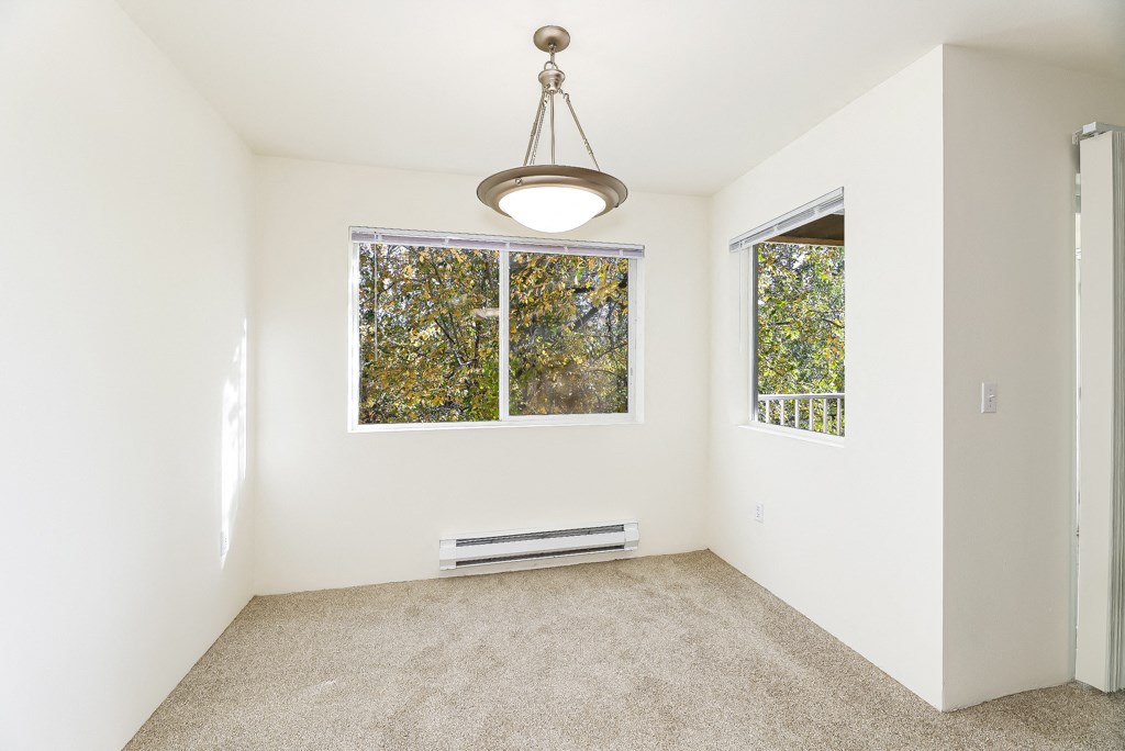 an empty room with a large window and a ceiling lamp