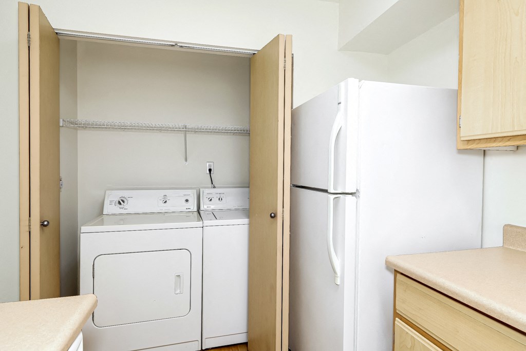 an empty kitchen with a washer and dryer and a refrigerator