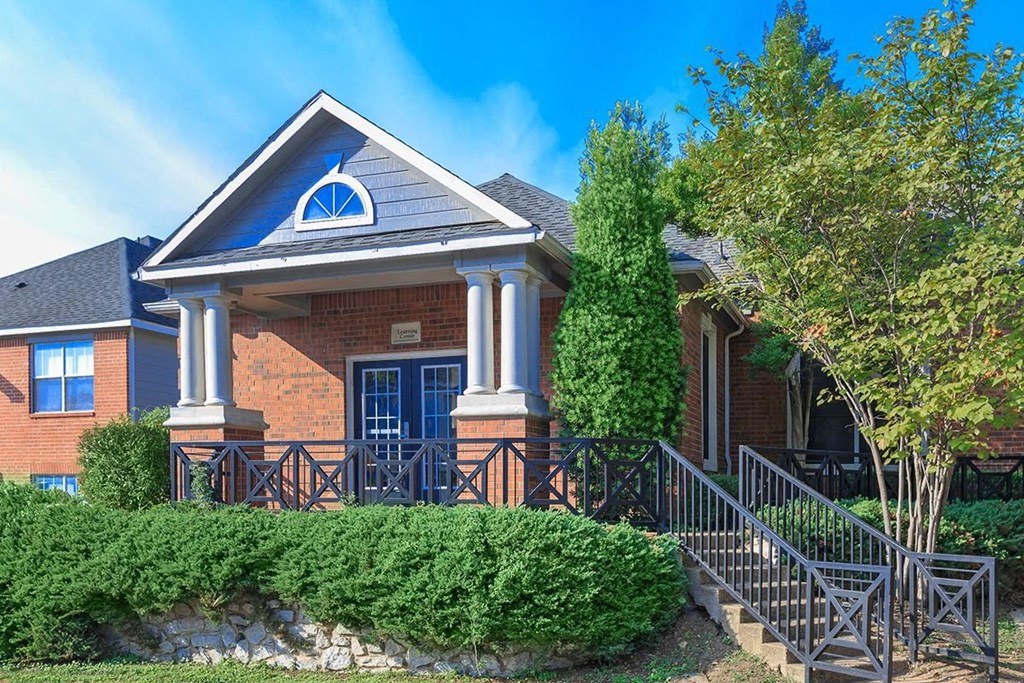 the front of a brick house with a porch and stairs