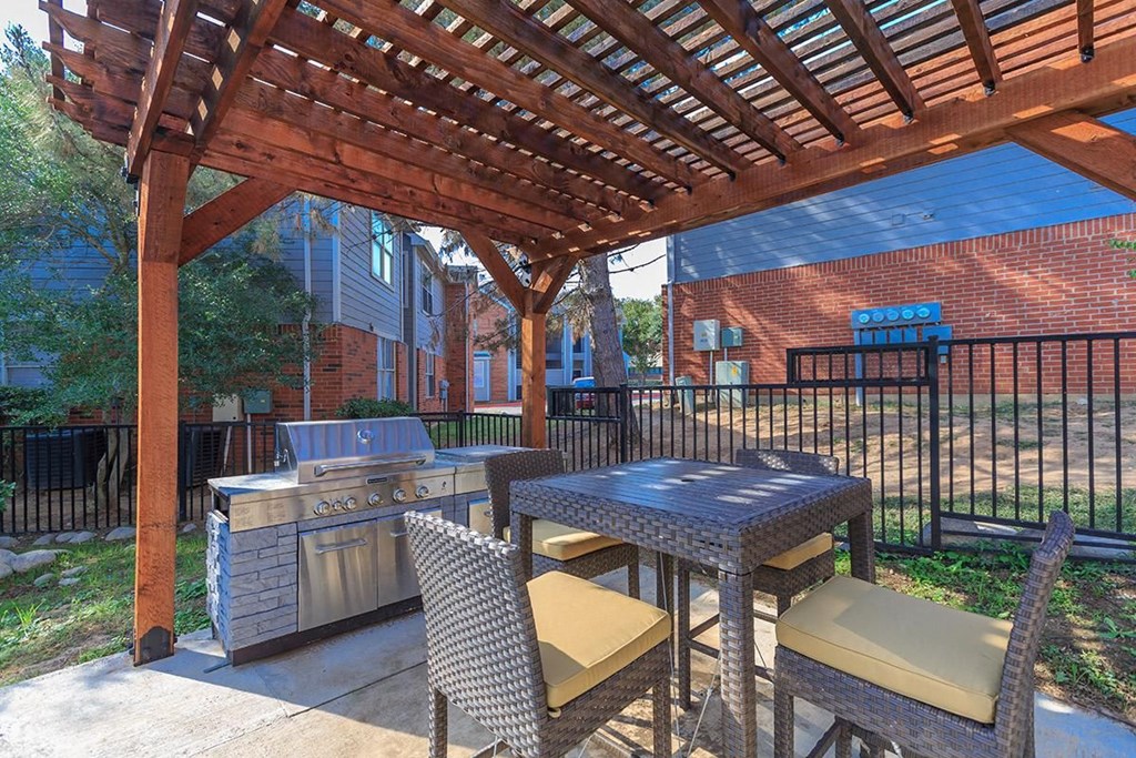 a patio with a picnic table and a grill