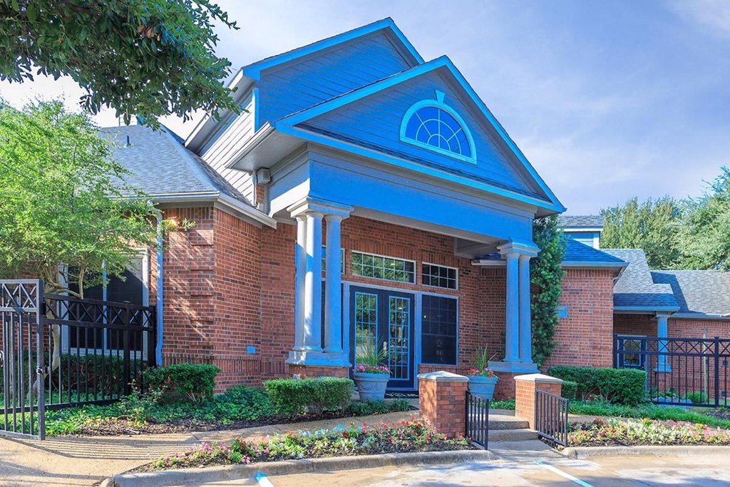 the front of a brick house with blue pillars and a black gate