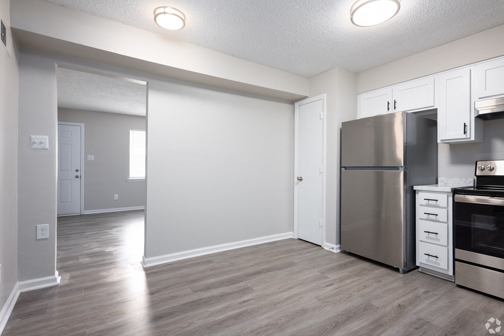 an empty kitchen with stainless steel appliances and white cabinets
