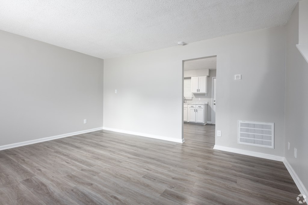an empty living room with wood floors and white walls
