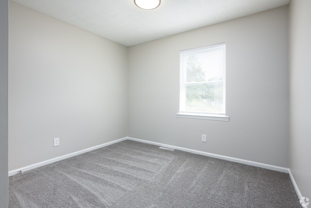 an empty room with carpet and a window