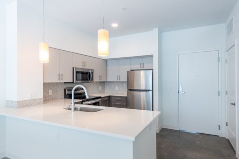 a white kitchen with stainless steel appliances and a white counter top