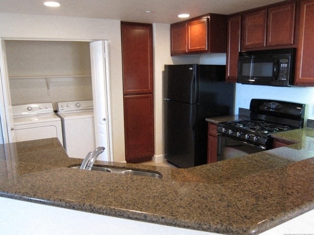 a kitchen with a granite counter top and a black refrigerator