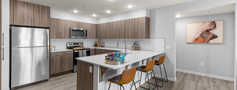 A modern kitchen with a refrigerator, microwave, oven, and a dining table with chairs.