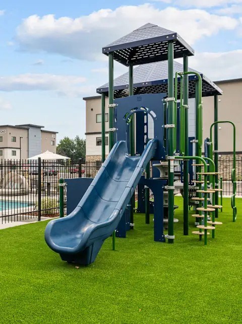 A playground with a blue slide and a green climbing structure.