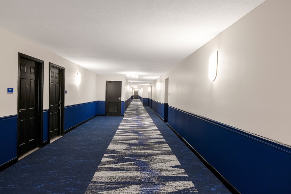 A long corridor with doors that has blue and white walls at Elme Alexandria, Virginia, 22304